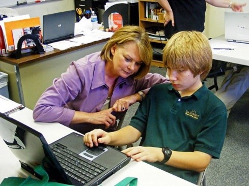 Adult watching a child use a computer